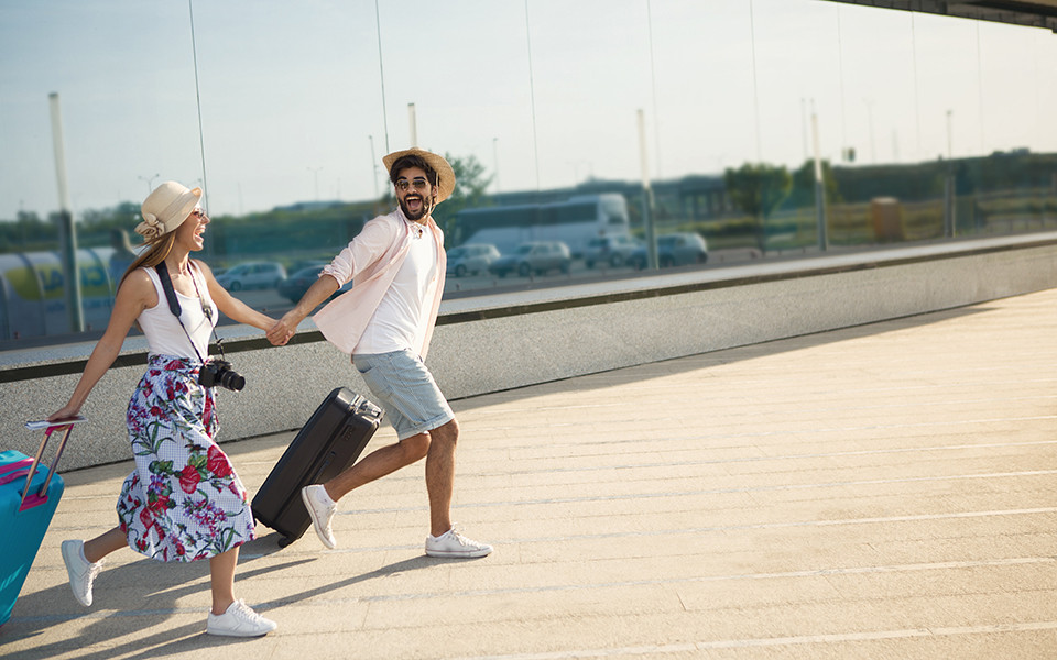 Paar startet in den Last Minute Urlaub mit gepackten Koffern